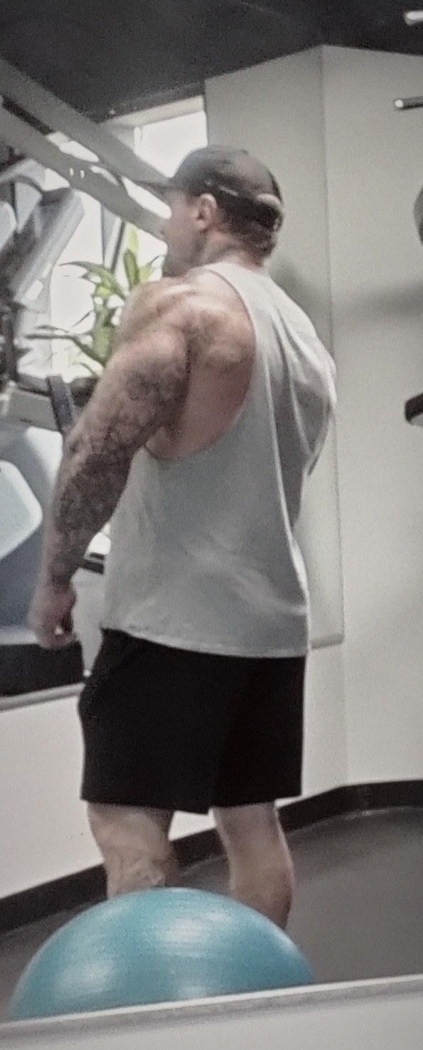 Phillip Walsh in the gym, seen from behind in a grey tank