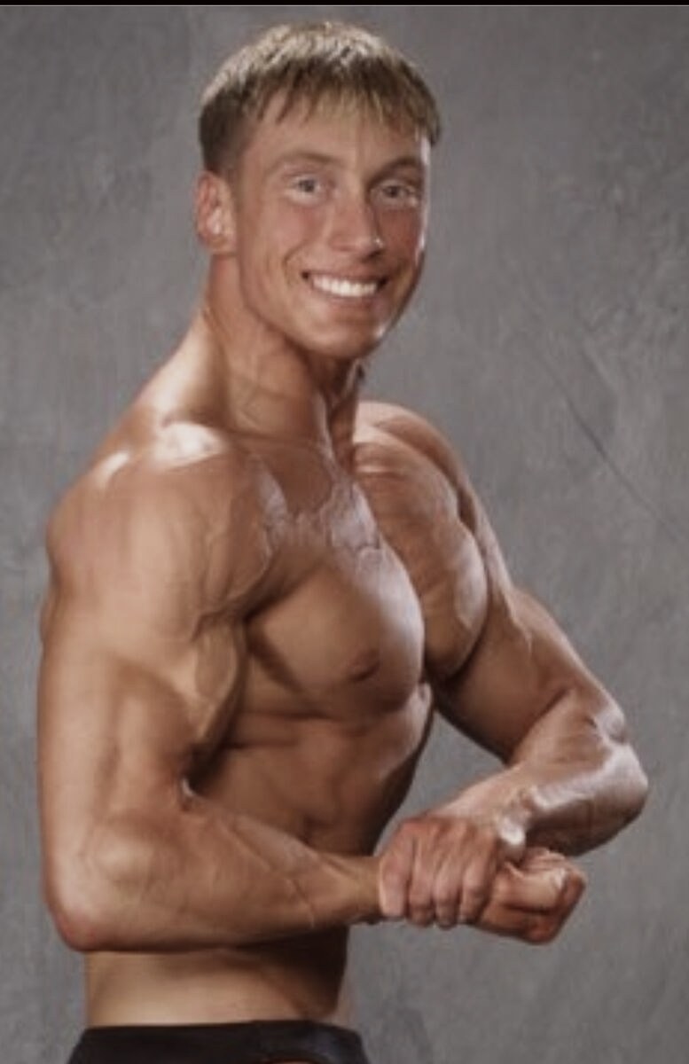 Phillip Walsh on stage in a side chest pose